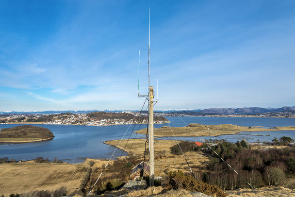 Antenna post στην κορυφή ενός λόφου στο προάστιο Tananger και γραφική θέα του φιόρδ Hafsfjord σε μια ωραία ηλιόλουστη ανοιξιάτικη μέρα, Νορβηγία, Μάρτιος 2018 - Φωτογραφία, εικόνα