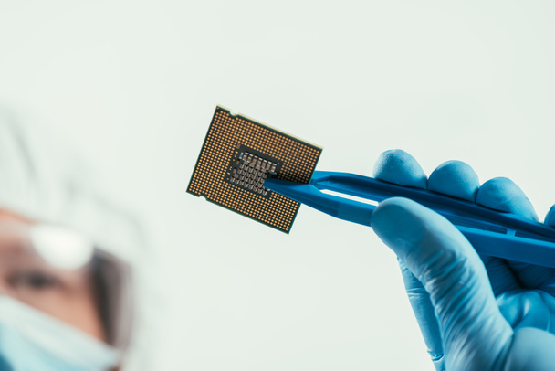 przycięty widok inżyniera trzymającego mikrochip komputerowy z pęsetą - Zdjęcie, obraz