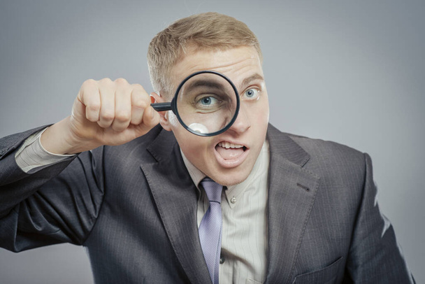 Funny image of a adult man with a magnifying glass, one eye is enlarged. - Valokuva, kuva
