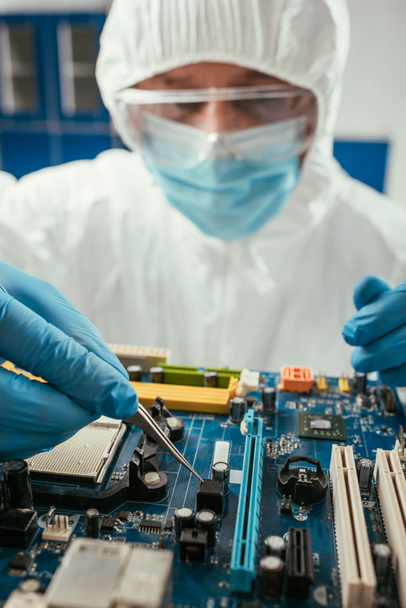 selective focus of engineer holding tweezers while testing computer motherboard - Photo, Image