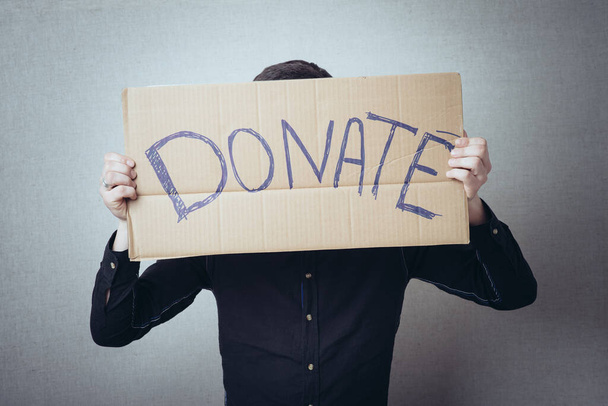 a man with an inscription on cardboard donate - Foto, Bild