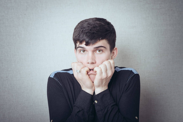 portrait of brunette man scared and keeps finger in mouth - Foto, immagini