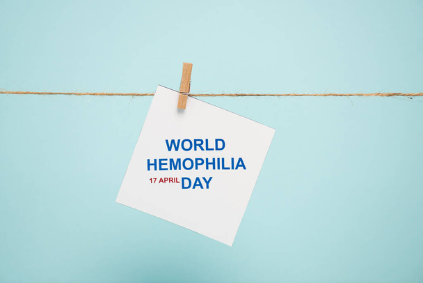Carte avec lettrage Journée mondiale de l'hémophilie sur corde avec broche isolée sur bleu
 - Photo, image