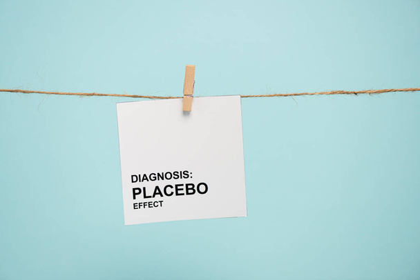 Karte mit Diagnose Placebo-Effekt Schriftzug auf Seil mit Stecknadel isoliert auf blau  - Foto, Bild