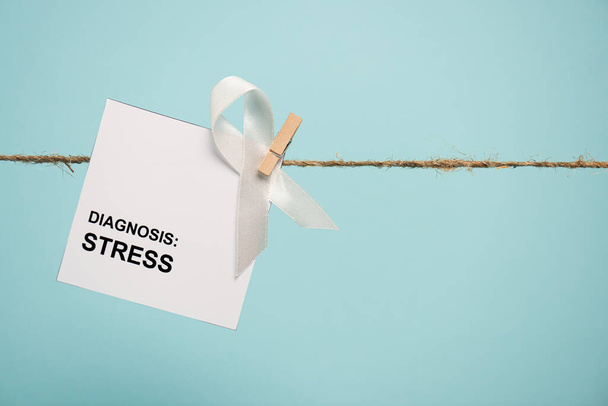 Tarjeta con letras de diagnóstico de estrés y cinta blanca en cuerda con pasador aislado en azul
  - Foto, Imagen