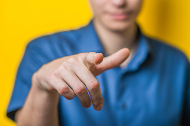 Male hand showing the index finger towards the camera, directing sign on a yellow background. Photo. - Фото, зображення
