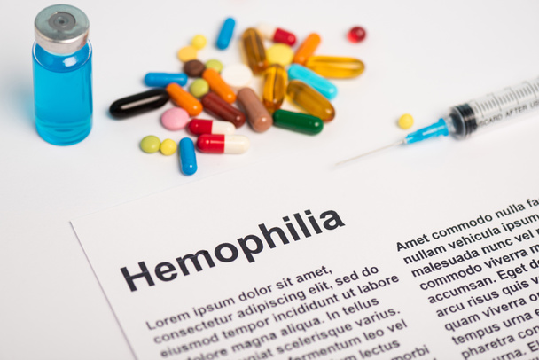 Paper with hemophilia lettering near syringe, vaccine and pills on white background - Foto, immagini
