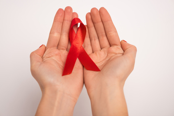 Cropped view of woman holding red ribbon of aids awareness on white background - Fotografie, Obrázek