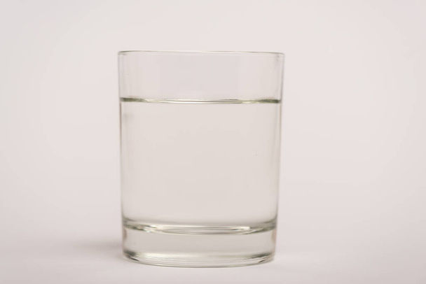 Крупним планом вид склянки води на білій поверхні
 - Фото, зображення