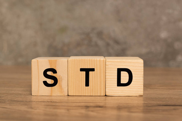 Wooden blocks with std letters on wooden table on grey background - Foto, afbeelding
