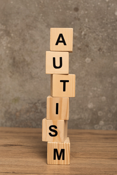Stacked blocks with autism lettering on wooden table on textured grey background - Fotografie, Obrázek