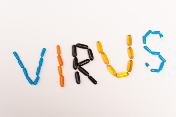 Draufsicht auf Virus-Schriftzug von Pillen auf weißem Hintergrund - Foto, Bild