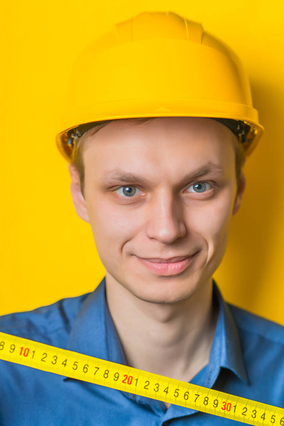 The builder in a helmet with a meter - Foto, immagini
