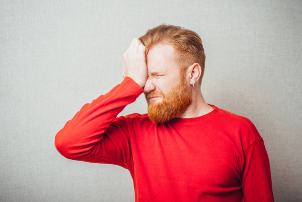 jonge roodharige man met baard met hoofdpijn - Foto, afbeelding
