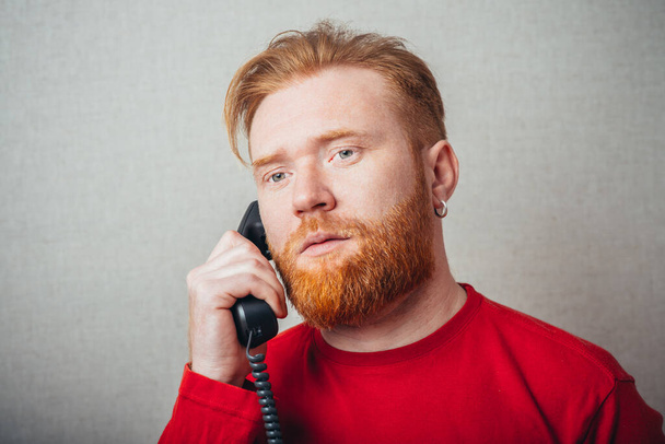 closeup portrait of Young hipster red bearded Man talking on corded retro phone  - Foto, immagini