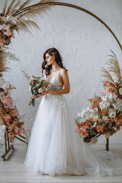 Happy bride in a wedding dress with a bouquet in her hands - Фото, зображення