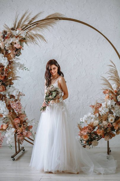 Happy bride in a wedding dress with a bouquet in her hands - Φωτογραφία, εικόνα