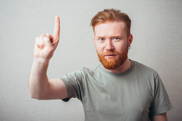 portrait of a bearded man shows his index finger up - Zdjęcie, obraz