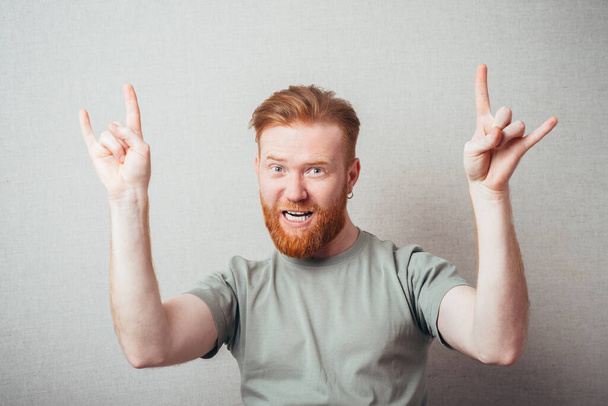 Attractive Young red bearded Man showing gesture hands of rock and roll  - Valokuva, kuva