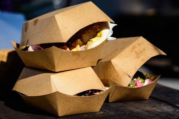 Tres cajas de cartón marrón para llevar expuestas en una mesa de madera en un mercado callejero de alimentos, listas para la venta y comen alimentos saludables
 - Foto, imagen
