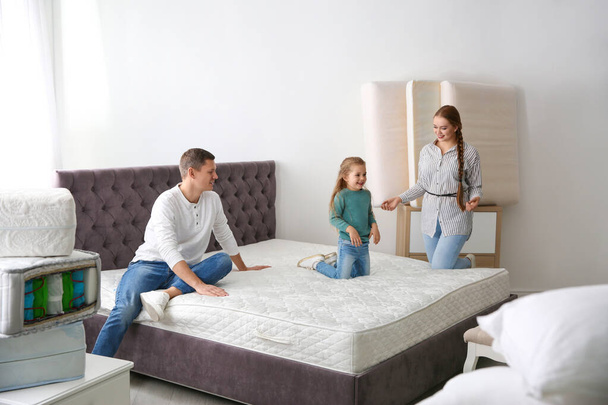 Happy family choosing mattress in furniture store - Foto, imagen