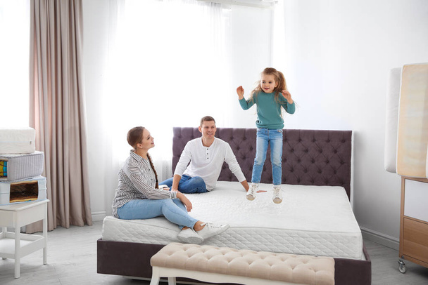 Happy family choosing mattress in furniture store - Foto, afbeelding