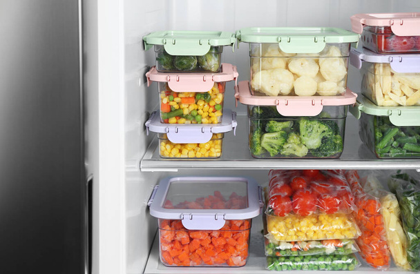 Plastic bags and containers with different frozen vegetables in refrigerator - Foto, immagini