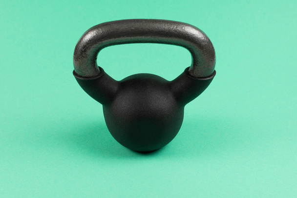 Black weight on green background. 4 kg weight. Fitness for women.  - Photo, Image