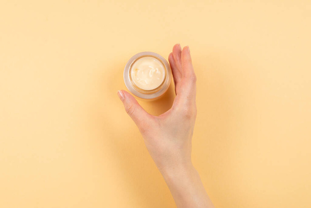 Hand cream and woman hands on a beige background. Copy space.  - Valokuva, kuva