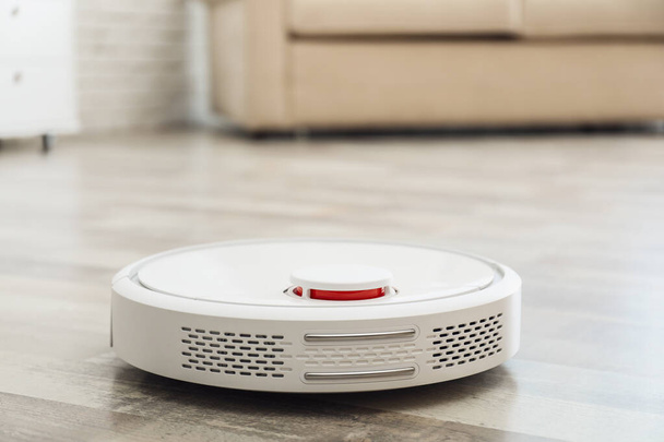 Modern robotic vacuum cleaner on floor in living room. Space for text - Foto, immagini