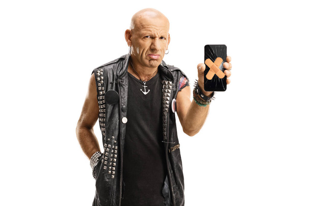Sad punk holding a broken mobile phone with adhesive plasters on the screen isolated on white background - Foto, Bild