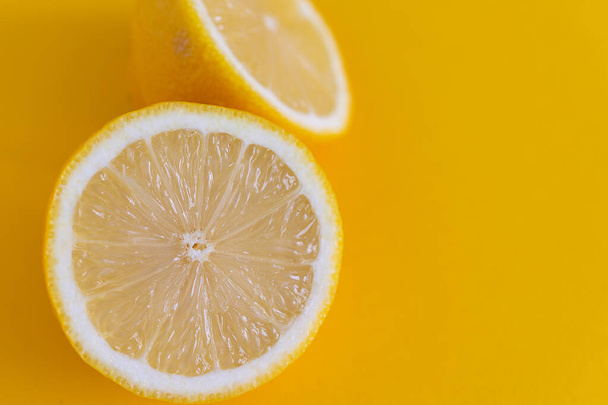 Primer plano de dos medias limones con enfoque selectivo, sobre fondo amarillo horizontalmente con espacio de copia
 - Foto, Imagen
