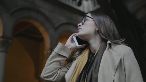 Žena mluví venku po smartphonu. Obchodnice kontroluje čas na náramkové hodinky - Záběry, video
