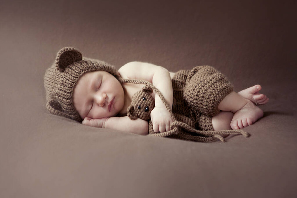 Sesión de bebé recién nacido. Retrato infantil de bebé. Dulce niña sobre un fondo de manta. Recién nacido con oso de peluche
 - Foto, imagen