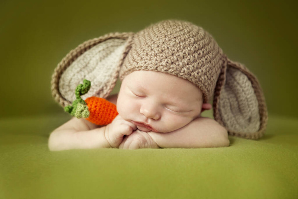 Sessione neonatale. Bambino col cappello da coniglio. Dolce tot bambino su uno sfondo verde
.  - Foto, immagini