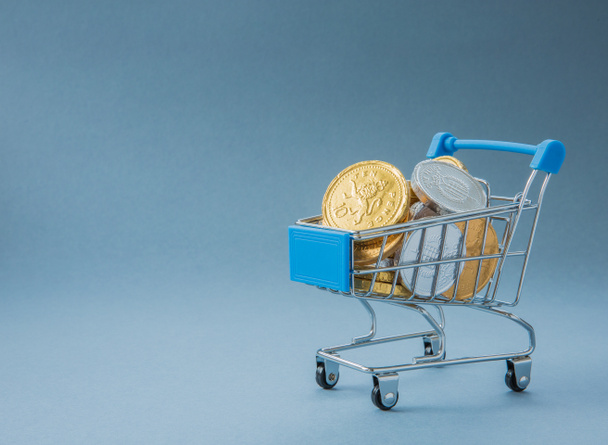 Concept d'un chariot ou d'un chariot de supermarché rempli d'argent comptant, de pièces de monnaie et d'argent représentant les dépenses des consommateurs dans les points de vente au détail avec espace de copie
 - Photo, image
