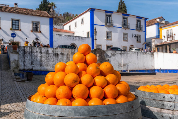 Barris de laranjas na praça ao lado da igreja de Santa Maria, Óbidos, Portugal
 - Foto, Imagem