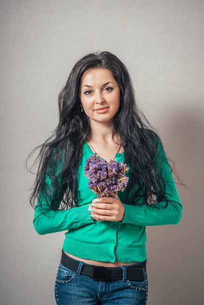 young smiling beautiful girl with the flowers, focus on the bouquet - Zdjęcie, obraz