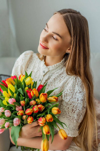 Beautiful young woman holds a multi-colored bouquet of tulips. Spring woman portrait. - Valokuva, kuva