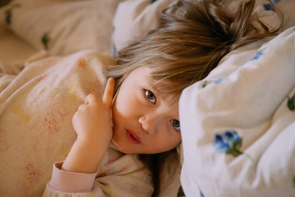 baby girl lying on a bed in her pajamas - Zdjęcie, obraz