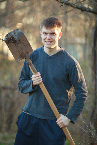 Agronomist handsome strong man with shovel on the background of flower beds - Photo, Image