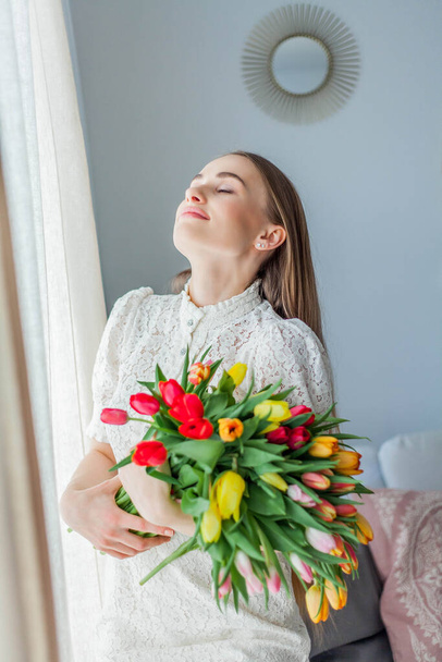Красивая молодая женщина держит разноцветный букет тюльпанов. Портрет весны
. - Фото, изображение