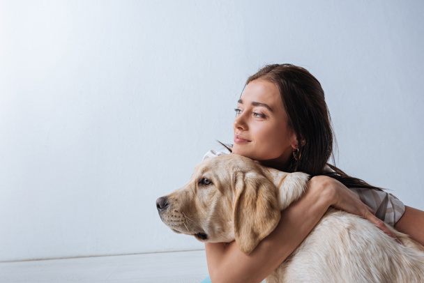 Attractive girl looking away while hugging golden retriever on white background  - Foto, immagini