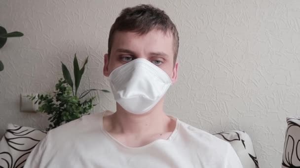 Έννοια της ασθένειας. Ο άντρας με τη μάσκα κοιτάζει με κούραση την κάμερα, βήχει και ξανακοιτά την κάμερα. Κρυολόγημα, γρίπη ή ιός - Πλάνα, βίντεο