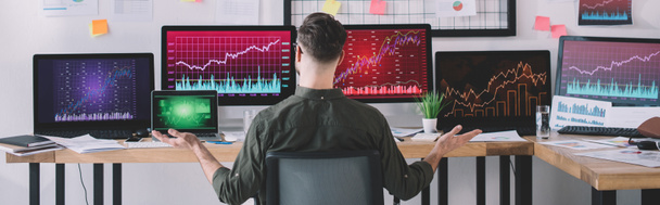 Achteraanzicht van data-analisten aan tafel met computers en grafieken op kantoor, panoramisch shot  - Foto, afbeelding