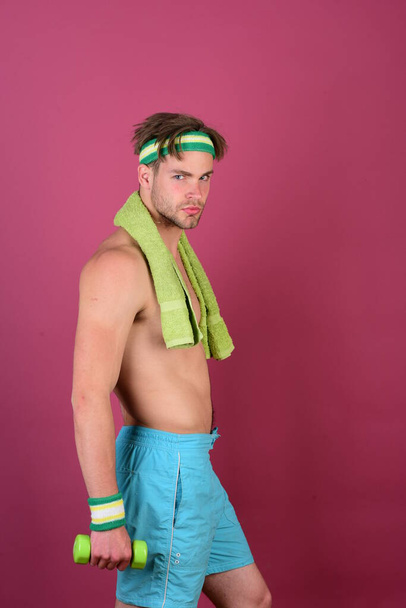 Man with naked torso holds towel on neck and dumbbell - Fotografie, Obrázek