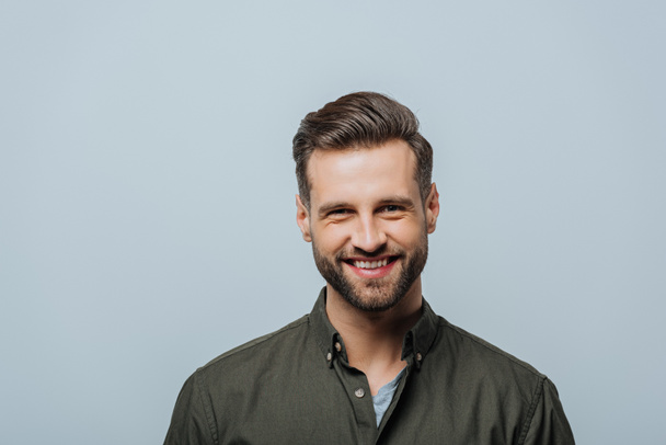 Handsome man smiling at camera isolated on grey - Foto, immagini