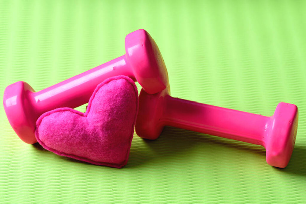 Love of sports and training. Heart decoration near plastic barbells - Foto, afbeelding