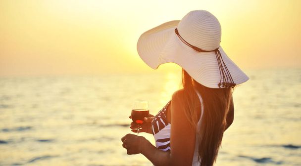 Mulher com copo de vinho ao pôr do sol na praia
. - Foto, Imagem