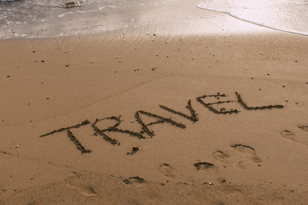 playa con letras de viaje en la arena cerca del mar
  - Foto, imagen